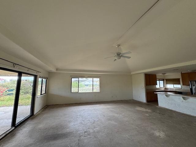 unfurnished living room featuring a ceiling fan, vaulted ceiling, and unfinished concrete floors