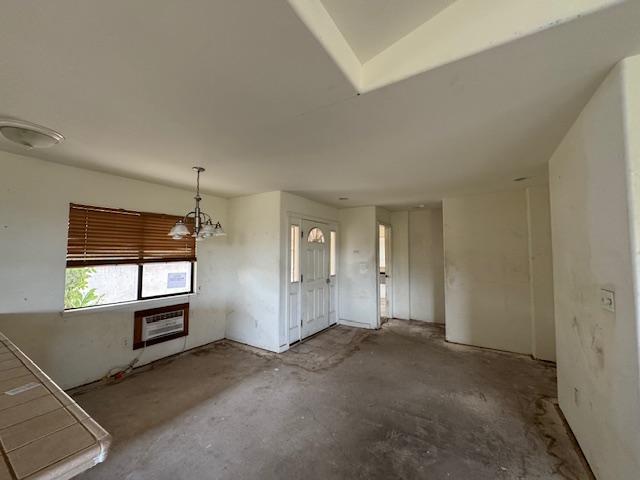 unfurnished living room featuring heating unit and unfinished concrete floors