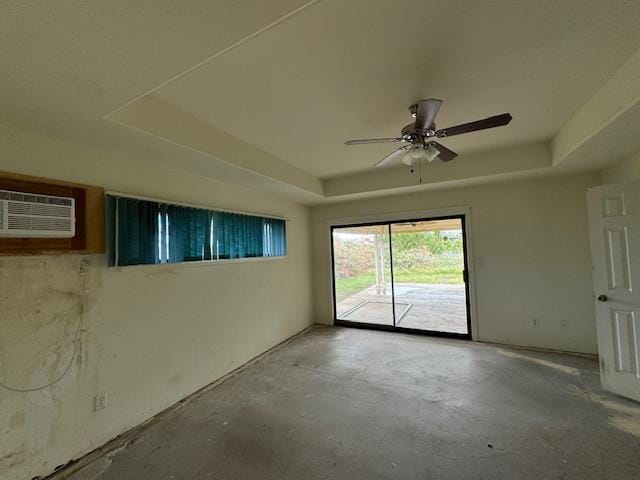 unfurnished room with a wall unit AC, a raised ceiling, and unfinished concrete flooring