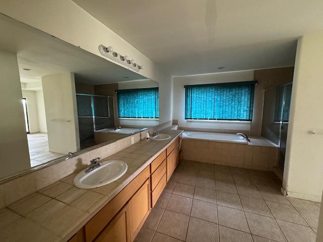 full bathroom with double vanity, tile patterned floors, a sink, a shower stall, and a bath