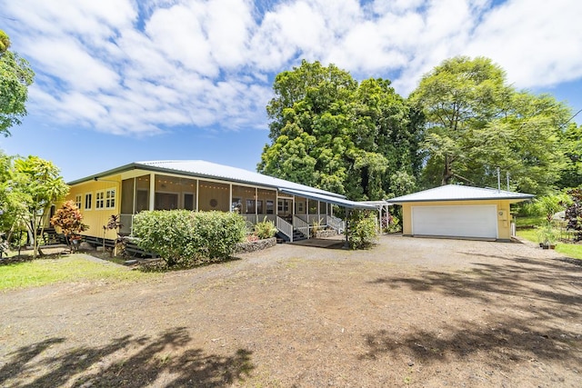 view of front of home featuring driveway, an outdoor structure, and a sunroom