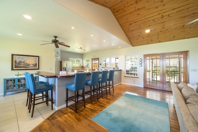 kitchen featuring a breakfast bar, stainless steel fridge with ice dispenser, light wood-style floors, and french doors