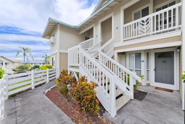 view of exterior entry featuring an AC wall unit and fence