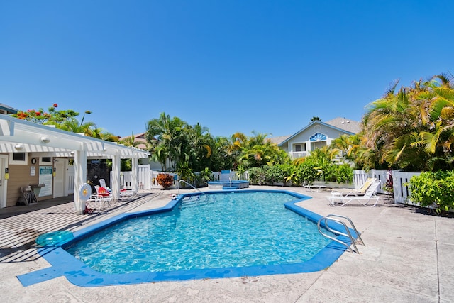 view of swimming pool featuring a patio area, fence, a pool with connected hot tub, and a pergola