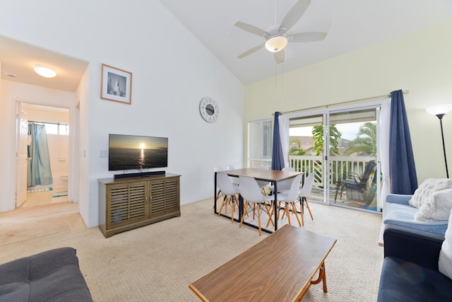 living area with high vaulted ceiling, ceiling fan, and carpet floors