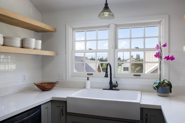 kitchen featuring black dishwasher, a sink, decorative backsplash, and open shelves