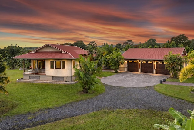 country-style home with gravel driveway, a front yard, stucco siding, metal roof, and an attached garage