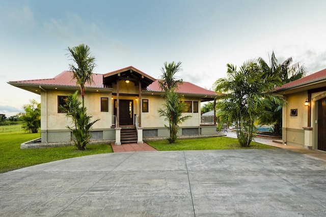 view of front of property with stucco siding, metal roof, and a front yard