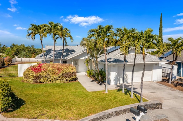 ranch-style house featuring concrete driveway, an attached garage, fence, roof mounted solar panels, and a front yard