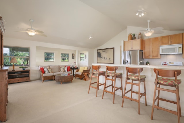 kitchen featuring white microwave, a healthy amount of sunlight, stainless steel refrigerator with ice dispenser, and light colored carpet