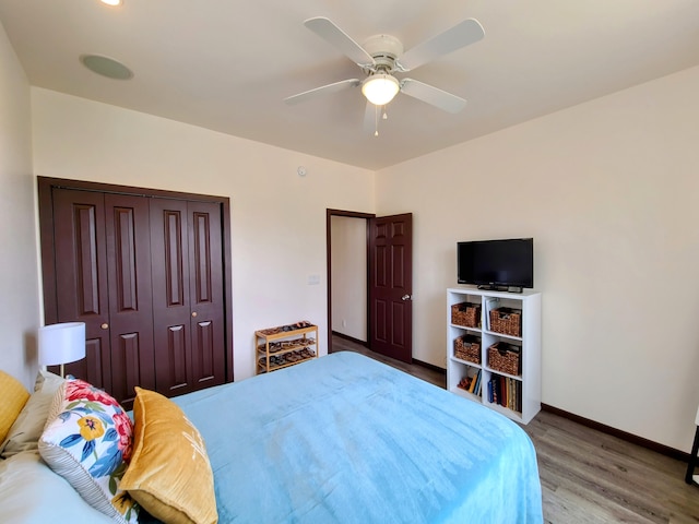 bedroom featuring a ceiling fan, a closet, baseboards, and wood finished floors