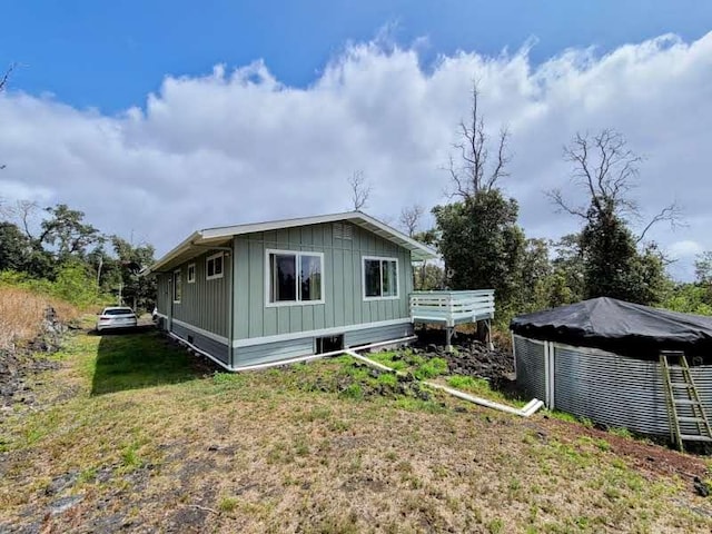 back of property with board and batten siding, a lawn, and a wooden deck