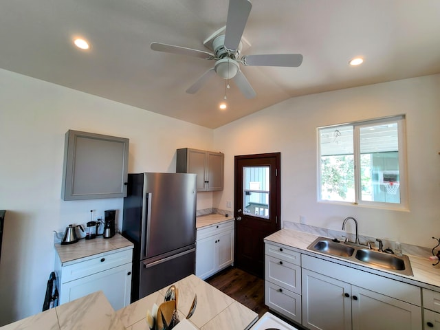 kitchen featuring gray cabinets, light countertops, freestanding refrigerator, vaulted ceiling, and a sink