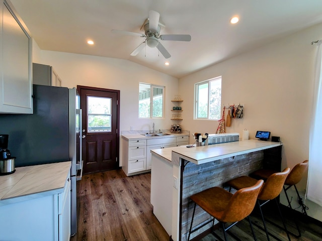 kitchen featuring light countertops, a sink, a breakfast bar area, and white cabinetry