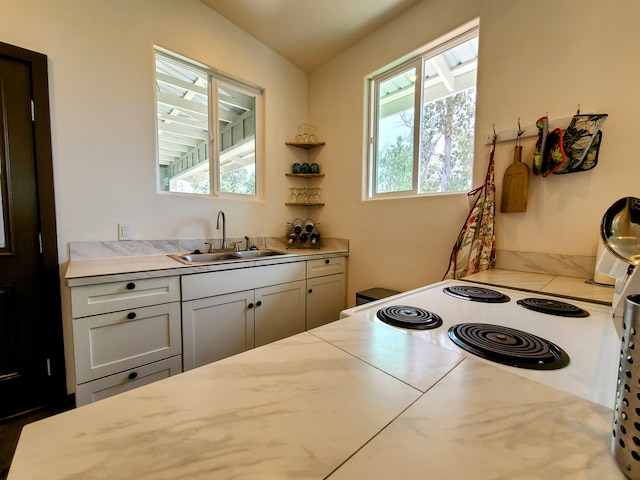 kitchen with light countertops, a sink, and white range with electric stovetop