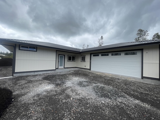 single story home with aphalt driveway, an attached garage, and metal roof