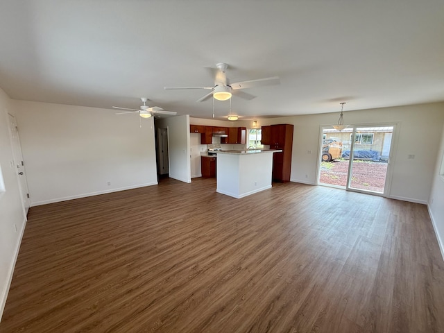 unfurnished living room with ceiling fan, baseboards, and dark wood finished floors