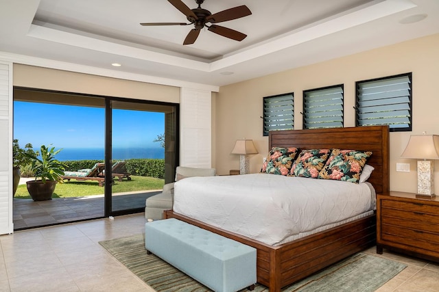 tiled bedroom featuring ceiling fan, access to outside, and a tray ceiling