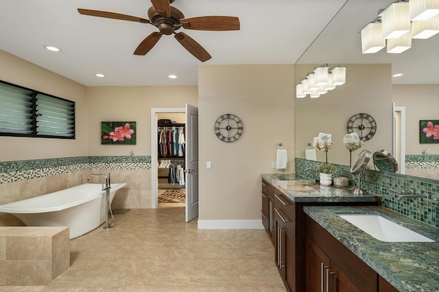 full bath with ceiling fan, a freestanding tub, recessed lighting, vanity, and a spacious closet