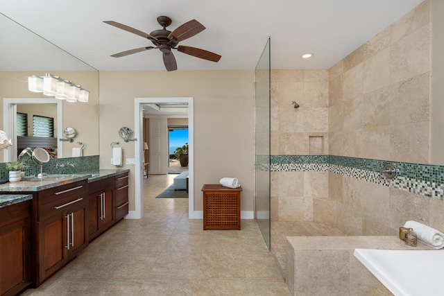 bathroom with a ceiling fan, vanity, tiled shower, baseboards, and tile patterned floors