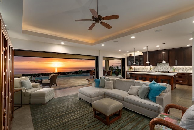 living area featuring ceiling fan, dark tile patterned flooring, a raised ceiling, and recessed lighting