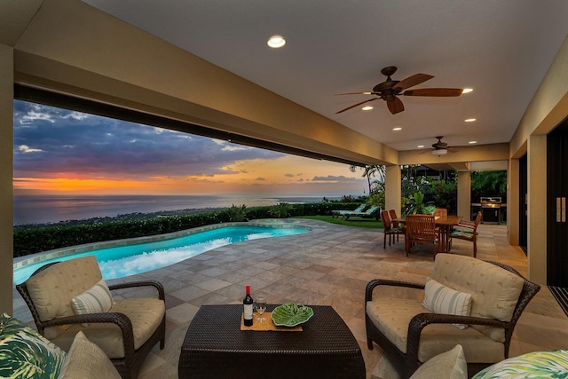 pool at dusk with outdoor dining area, a ceiling fan, an outdoor living space, an outdoor pool, and a patio area