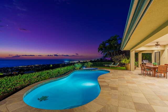 pool at dusk featuring a patio, outdoor dining space, a water view, and an outdoor pool