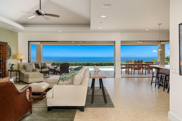 living area with a tray ceiling, a healthy amount of sunlight, and a water view