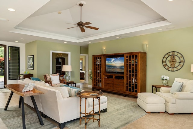 living room with a ceiling fan, a tray ceiling, recessed lighting, and light tile patterned floors