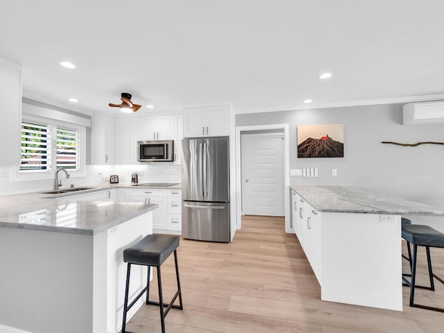 kitchen with a peninsula, a breakfast bar area, appliances with stainless steel finishes, and a sink