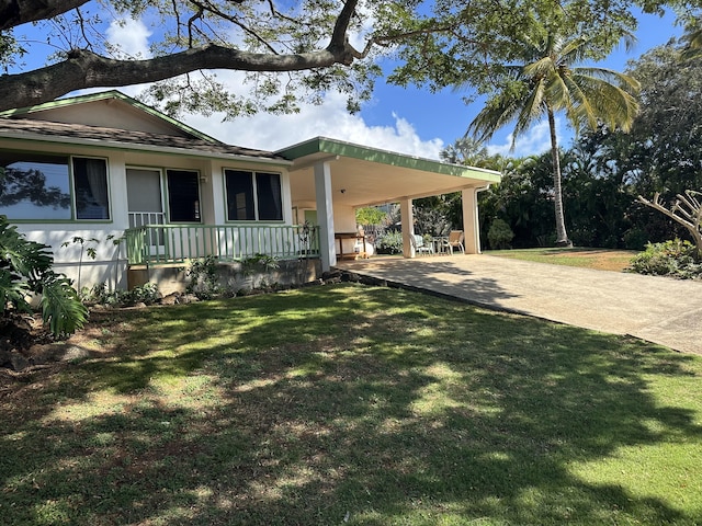 view of side of property with driveway, a carport, a porch, and a lawn