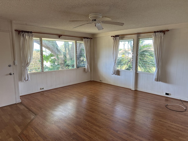 empty room with a ceiling fan, a textured ceiling, and wood finished floors