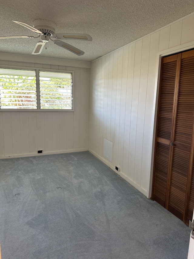 carpeted spare room featuring a textured ceiling and ceiling fan