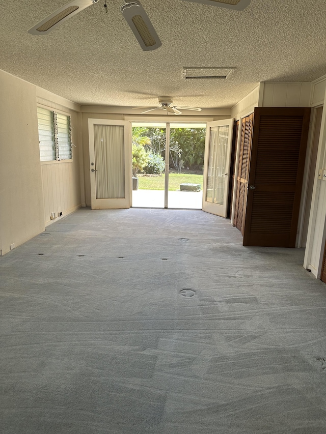 interior space with plenty of natural light, a textured ceiling, ceiling fan, and carpet flooring