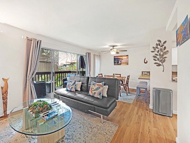 living area featuring light wood-type flooring, baseboards, and ceiling fan