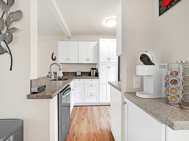 kitchen featuring a sink, light wood-style floors, dishwasher, and white cabinets