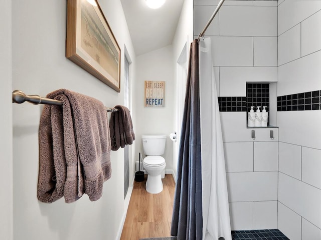 full bath featuring baseboards, tiled shower, toilet, and wood finished floors