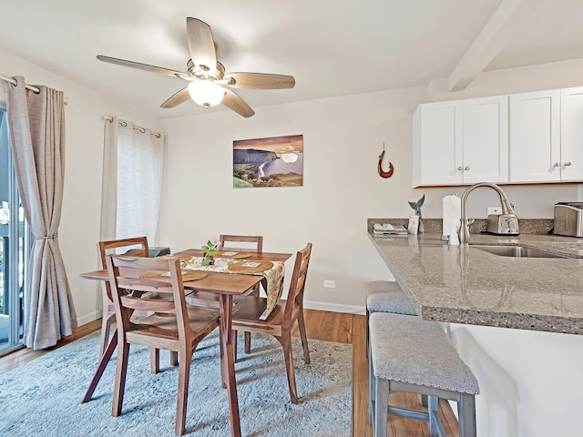 dining area with baseboards, light wood-style floors, and ceiling fan