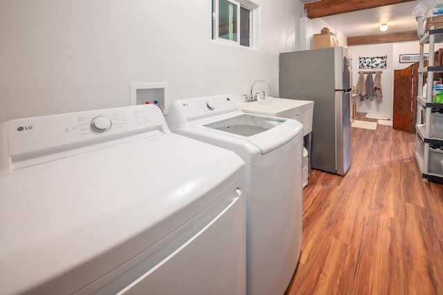 laundry area with laundry area, light wood-type flooring, a sink, and washer and dryer