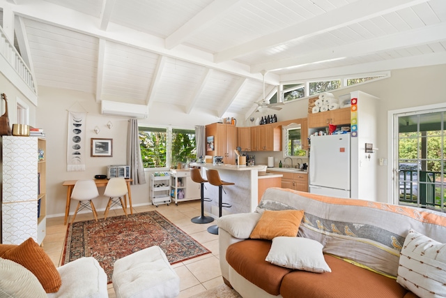 living area featuring an AC wall unit, lofted ceiling with beams, baseboards, and light tile patterned floors