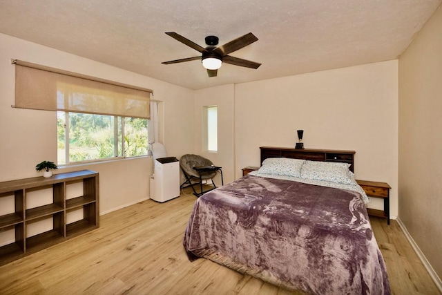 bedroom with light wood-type flooring, baseboards, and a ceiling fan