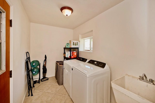 laundry area featuring light tile patterned floors, laundry area, a sink, baseboards, and washing machine and clothes dryer