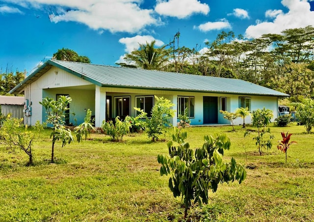 back of property with metal roof and a lawn