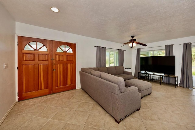 living area with a textured ceiling, light tile patterned floors, and a ceiling fan