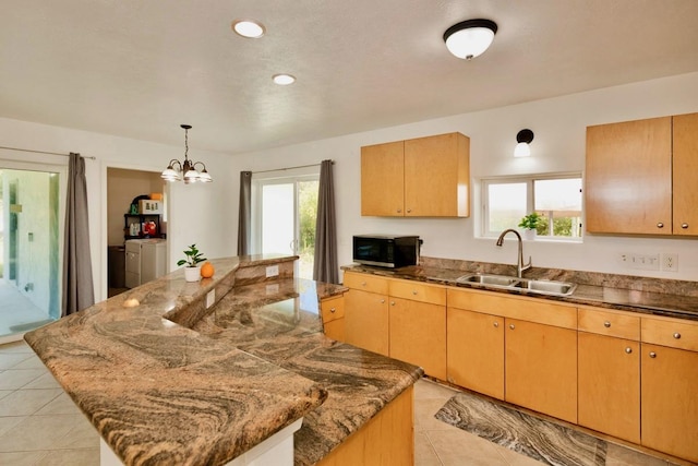 kitchen featuring black microwave, separate washer and dryer, a kitchen island, a sink, and plenty of natural light