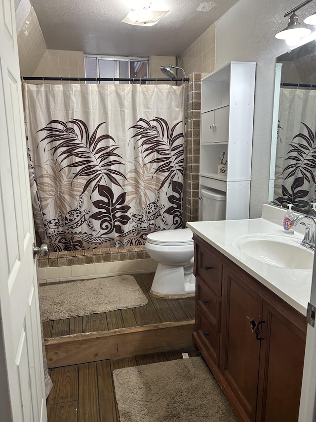 bathroom with vanity, wood finished floors, toilet, a shower with shower curtain, and a textured ceiling