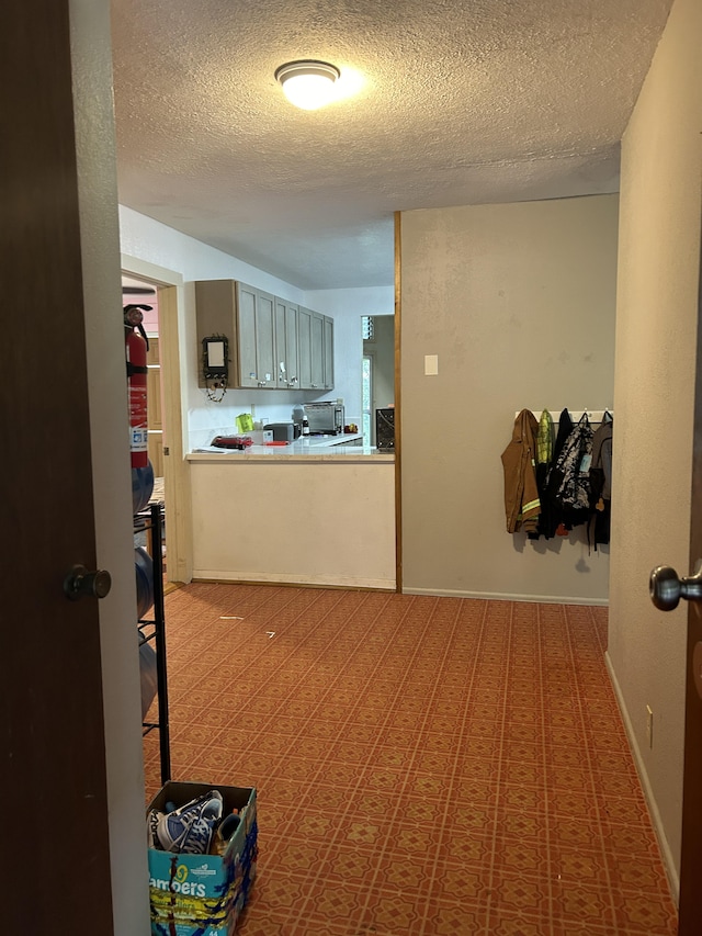 corridor featuring a textured ceiling and baseboards