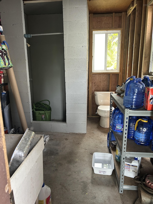 bathroom with unfinished concrete floors and toilet