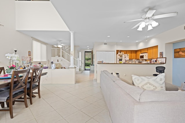 living room featuring ceiling fan, light tile patterned floors, recessed lighting, stairs, and decorative columns