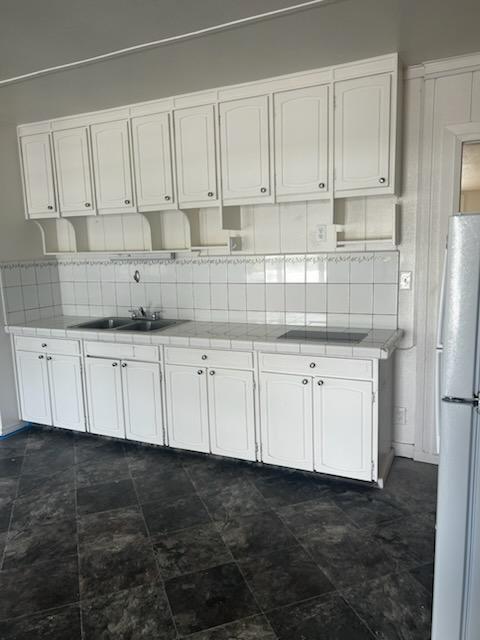 kitchen featuring white cabinetry, tile counters, tasteful backsplash, and freestanding refrigerator